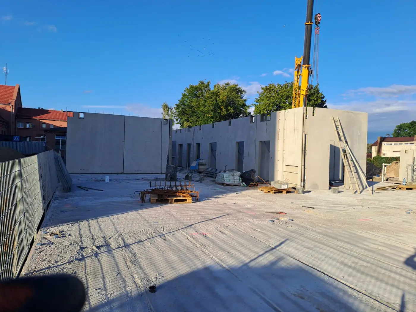 Ściany parteru ustawione na stropie nad kondygnacją podziemną, w tle żuraw montażowy