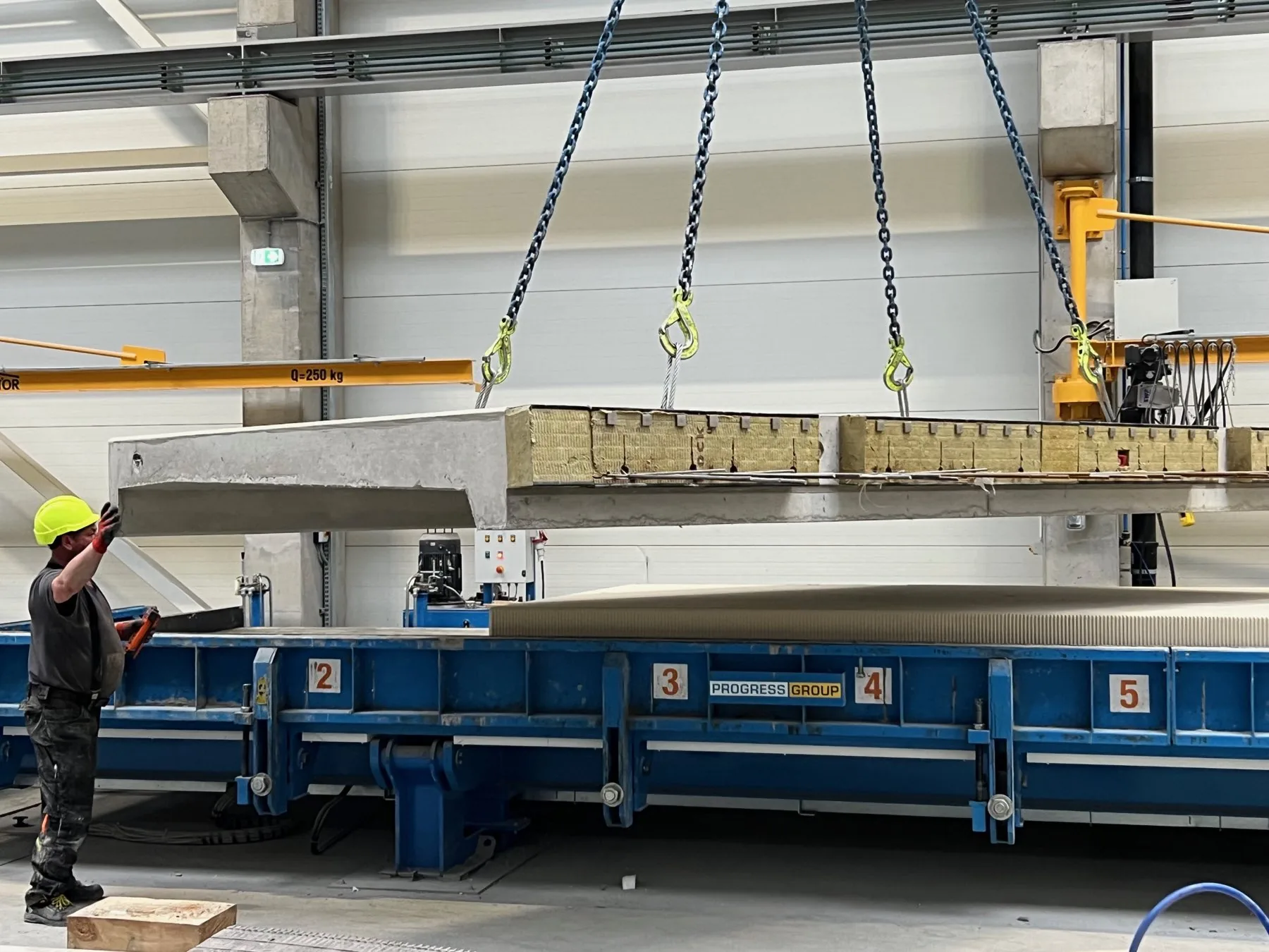 Vorgefertigte Balkonplatte wird in der Formee-Produktionshalle mit dem Kran aus der Form gehoben, an der Kante die sichtbare Dämmeinlage