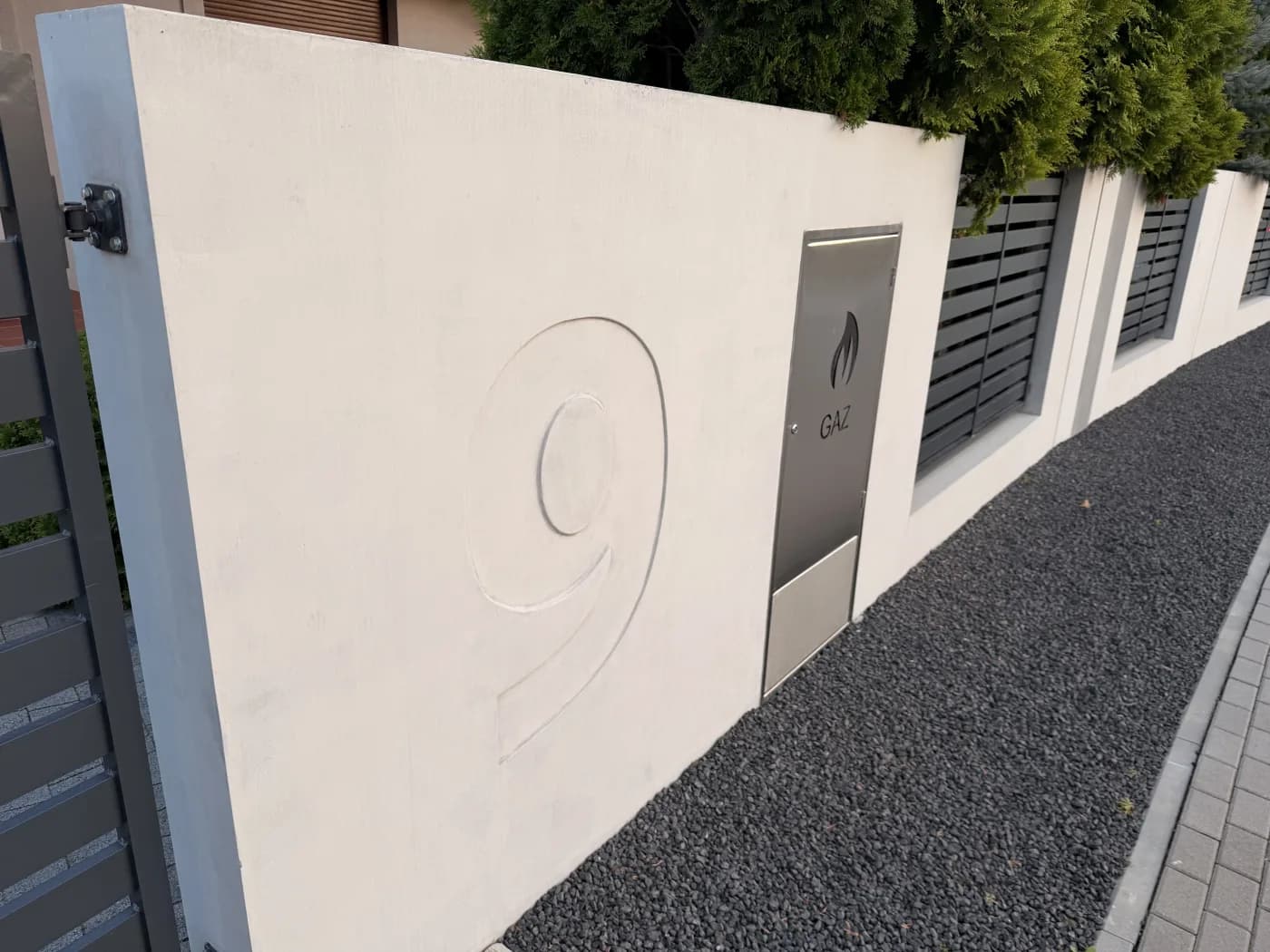 Pylon ogrodzenia z betonu architektonicznego z wtopionym reliefem numeru domu i szafką gazową ze stali nierdzewnej