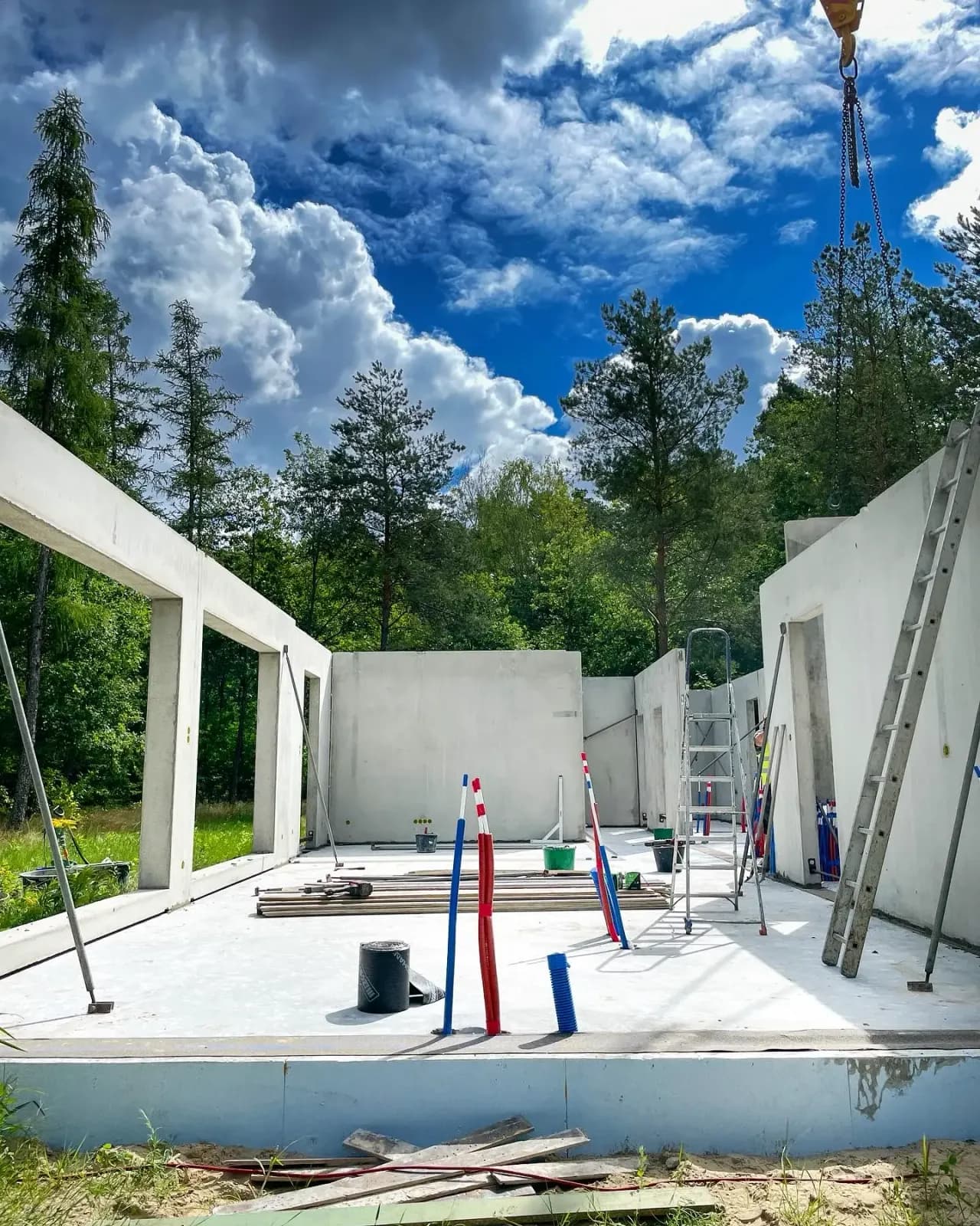 Ściany parteru z prefabrykatów ustawione na płycie fundamentowej i podparte zastrzałami — stan surowy otwarty w budowie